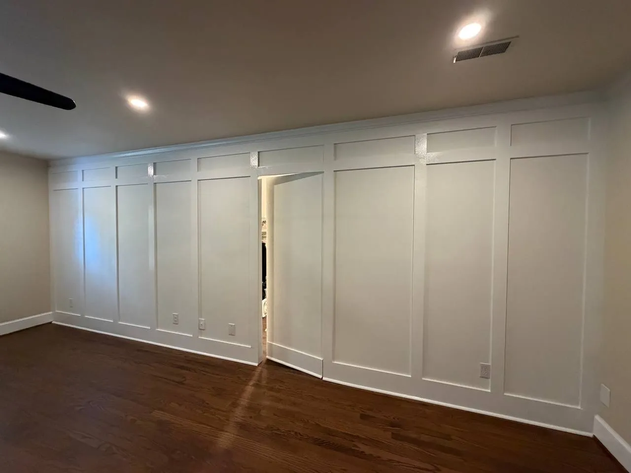 Full-height white board and batten wall in a bedroom, with the closet door built into the paneling