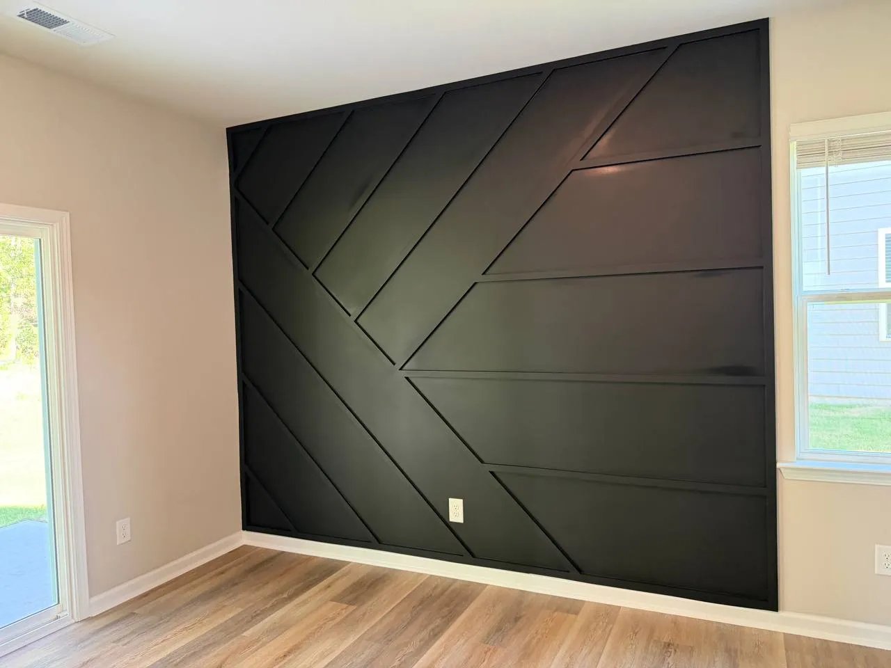 Black geometric accent wall with angled trim across a living room wall